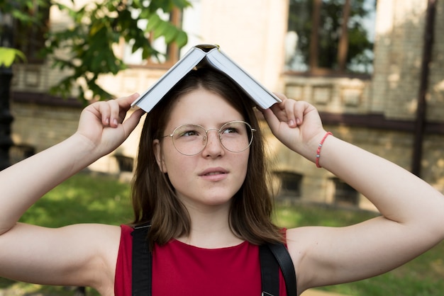 Photo gratuite lycée tenant un livre ouvert sur la tête