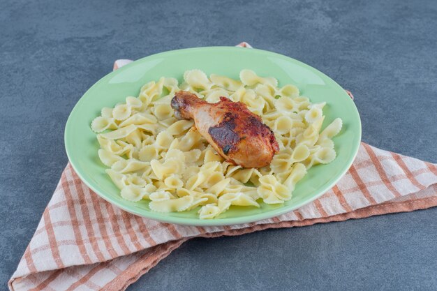 Macaroni bouilli et cuisse de poulet sur plaque verte.