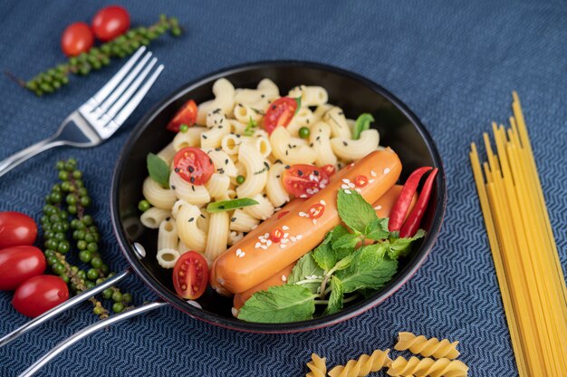 Macaroni frit et saucisse dans une poêle.