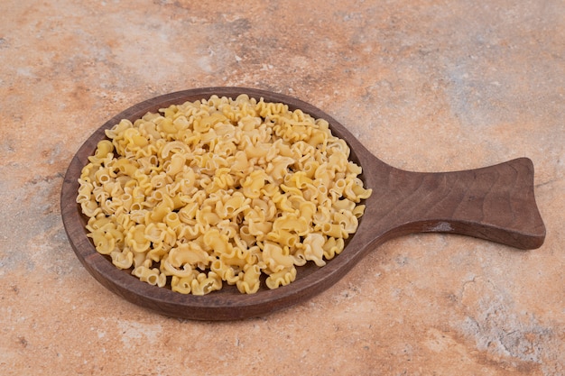 Macaroni non cuit frais sur planche de bois sur fond de marbre