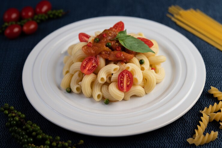 Photo gratuit macaroni sauté à la tomate, au piment, aux graines de poivre et au basilic dans un plat blanc.