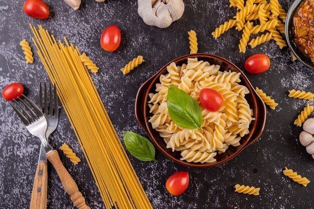 Macaroni sautés aux tomates et basilic sur une assiette grise.