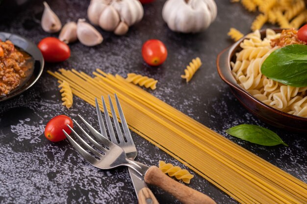 Macaroni sautés aux tomates et basilic sur une assiette grise.