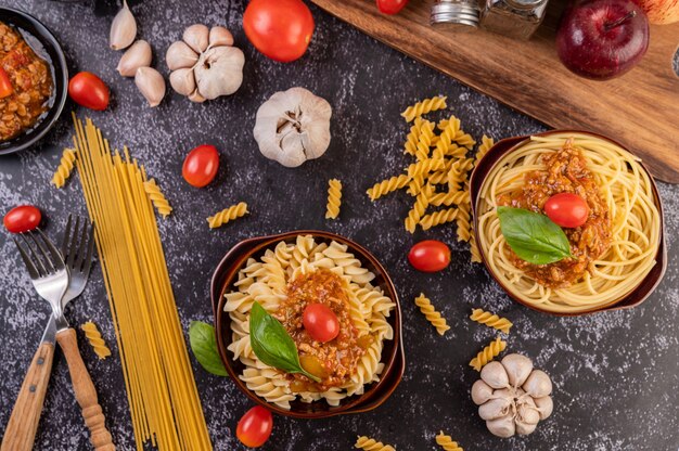 Macaroni sautés aux tomates et basilic sur une assiette grise.