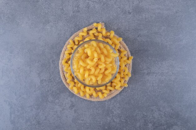 Macaroni sec cru dans un bol en verre.