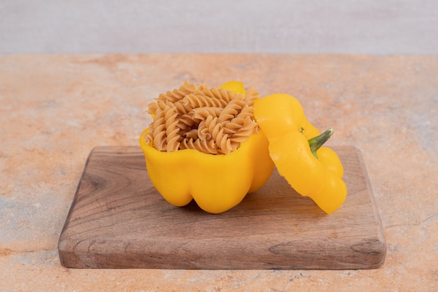 Macaroni en spirale non cuit brun avec du poivre sur planche de bois