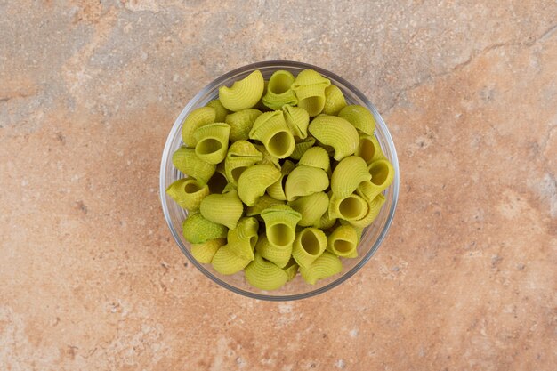 Macaroni vert non préparé en plaque de verre sur fond de marbre. Photo de haute qualité