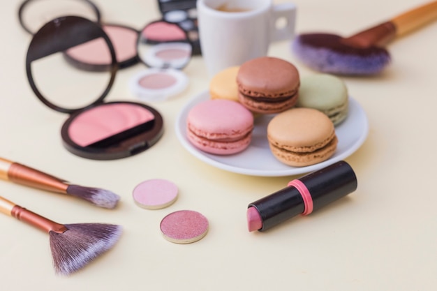 Photo gratuite macarons colorés avec des produits cosmétiques sur fond beige