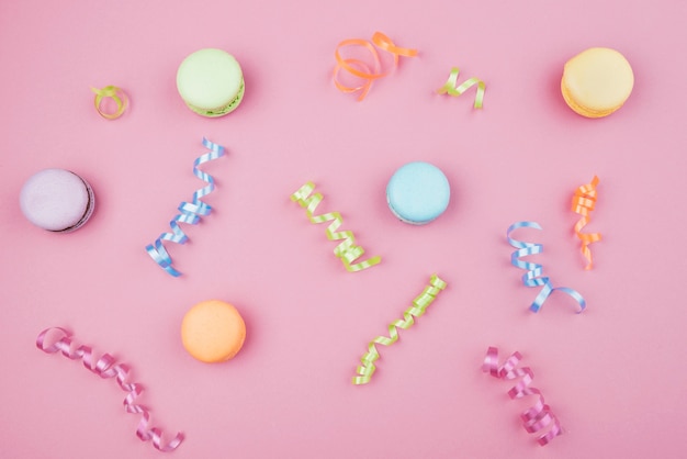 Macarons multicolores avec des confettis sur fond rose