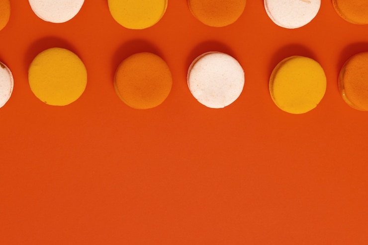 Photo gratuit macarons savoureux à plat sur fond de corail