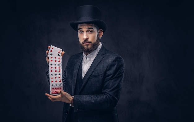 Photo gratuite magicien montrant un tour avec des cartes à jouer sur un fond sombre.