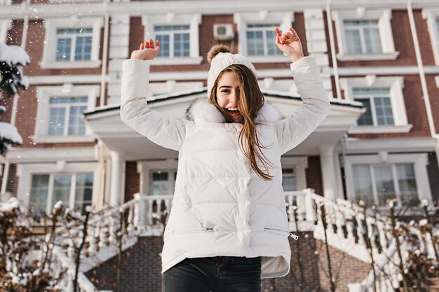 Magnifique femme brune sautant devant la maison. Photo extérieure de jolie jeune femme