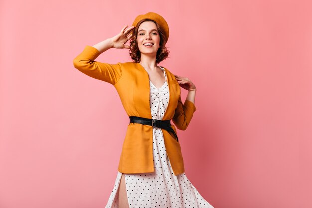 Magnifique fille française regardant la caméra avec le sourire. Photo de Studio de jeune femme glamour au béret jaune.