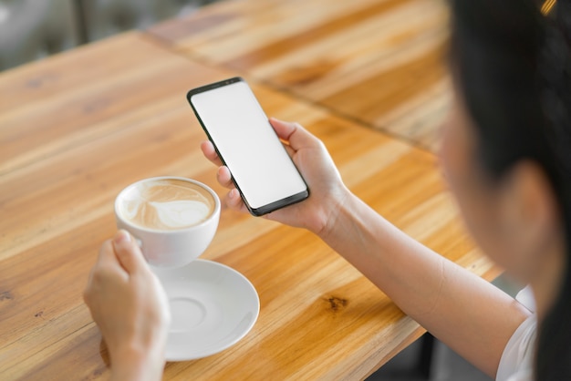 Main d&#39;affaires avec le téléphone mobile et le café d&#39;art latte.