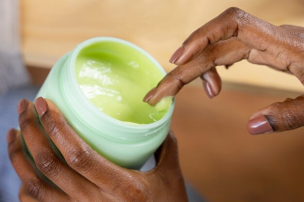 Main à angle élevé tenant un récipient à crème