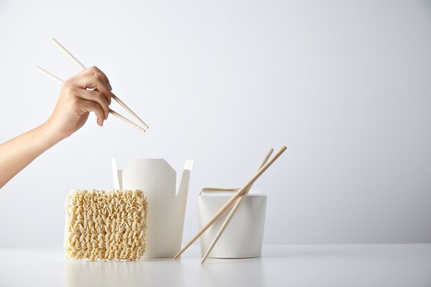 La main avec des baguettes prêtes au-dessus des boîtes à emporter ouvertes et fermées