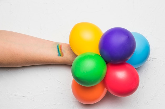Main avec des ballons et des rayures aux couleurs LGBT