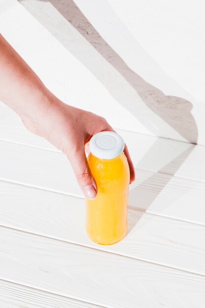 Main avec une bouteille de jus d&#39;orange
