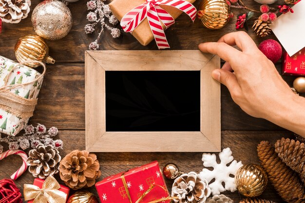 Main avec cadre photo entre les décorations de Noël