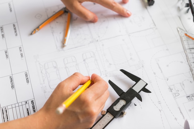 La main sur la construction des plans avec un casque jaune et outil de dessin