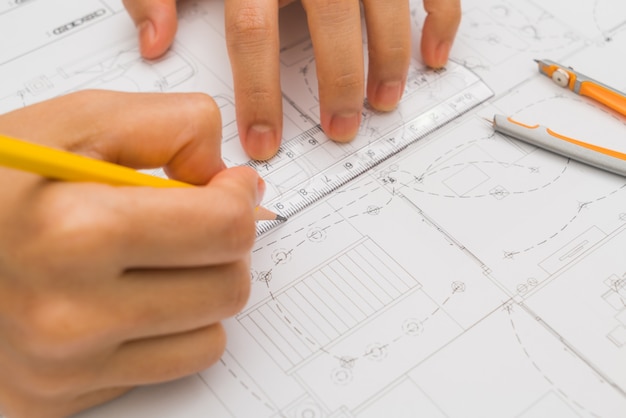 La main sur la construction des plans avec un casque jaune et outil de dessin