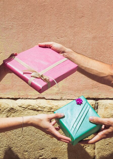 La main d&#39;un couple s&#39;offrant un cadeau de Saint-Valentin devant un mur