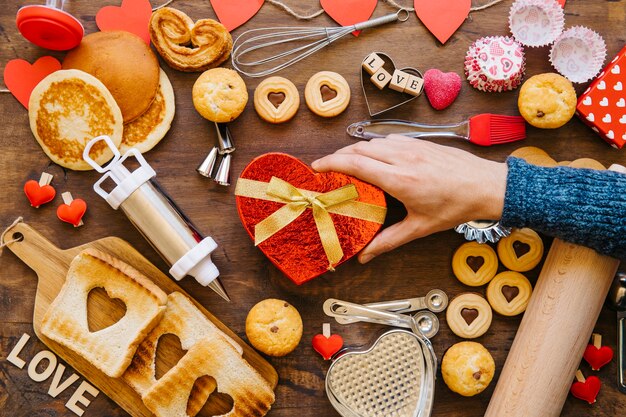 Photo gratuite main de la culture mettant le présent près de la pâtisserie