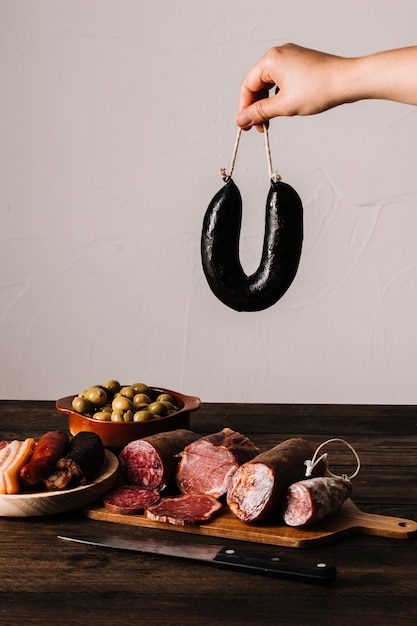 Photo gratuite main de culture tenant la saucisse sur la nourriture