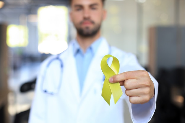 Main de docteur avec ruban d'or jaune, sensibilisation au sarcome, sensibilisation au cancer infantile, journée mondiale de prévention du suicide.