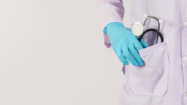 Main de docteur et stéthoscope. portez à la main le gant médical bleu et une robe à manches longues sur fond blanc.