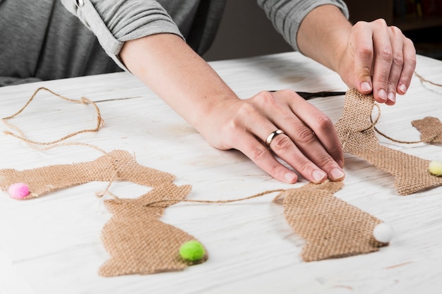 Photo gratuite main faisant la forme de lapin bunting de vêtements de jute sur la table