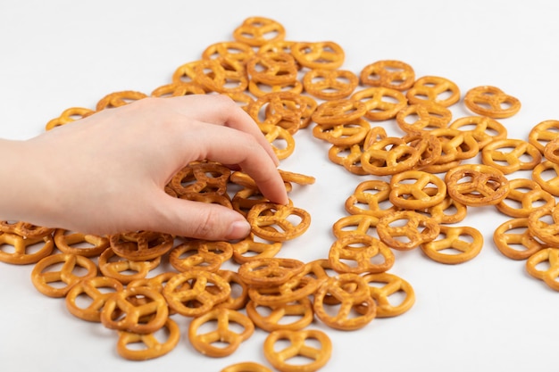 Main féminine affectant des craquelins bretzels secs salés placés sur une surface blanche