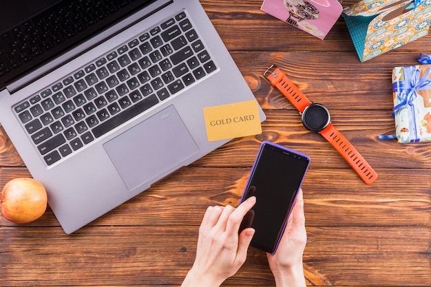 Main féminine à l&#39;aide d&#39;un téléphone portable sur une surface en bois