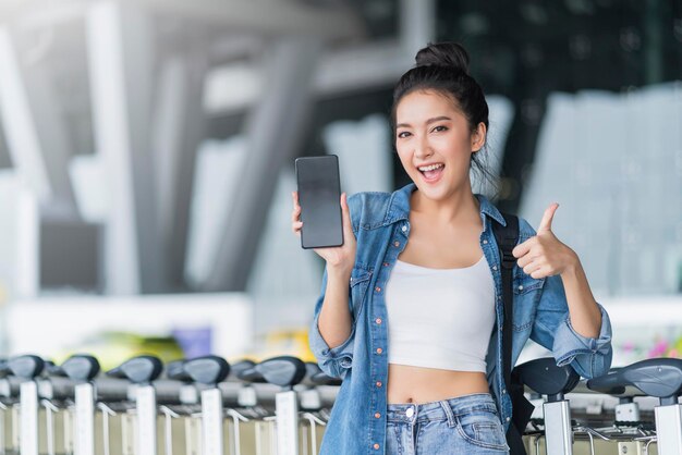 Main féminine asiatique attrayante et intelligente tenir un smartphone en vérifiant l'horaire des taxis sur l'écran de l'application idées de voyage en ville intelligente