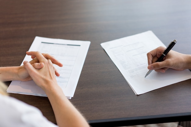 Main féminine remplissant un questionnaire pour un candidat masculin.