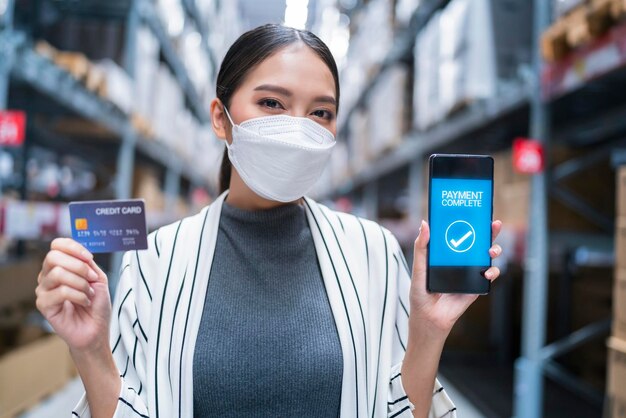 Main féminine tenant une carte de crédit sur fond d'entrepôtCarte de crédit au lieu d'un concept de paiement en espèces Carte bancaire en plastique maquette modèle concept d'idées commerciales