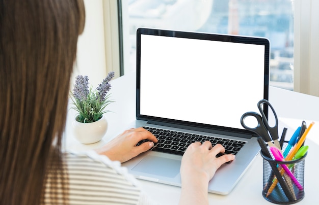 Main de femme d&#39;affaires à l&#39;aide d&#39;un ordinateur portable avec un écran blanc sur le bureau