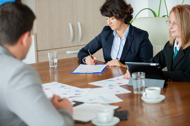 Main de femme d'affaires signant un contrat dans la salle de réunion. Image en gros plan