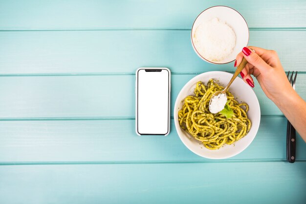 Main de femme ajoutant l&#39;assaisonnement sur les spaghettis