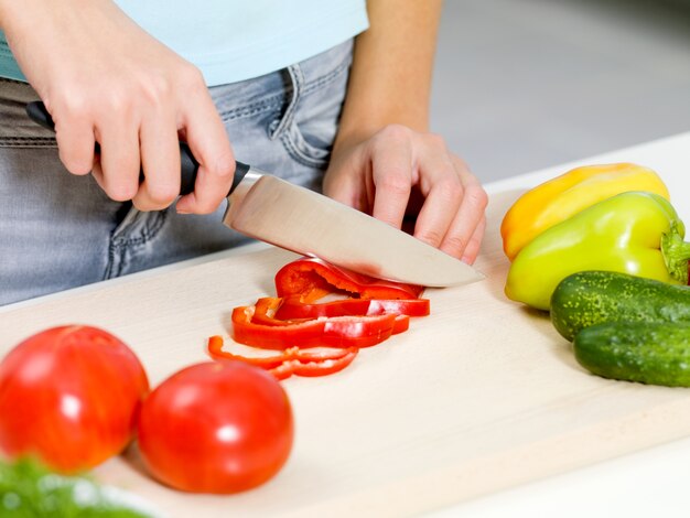 Main de femme couper les légumes sur le bureau de la cuisine