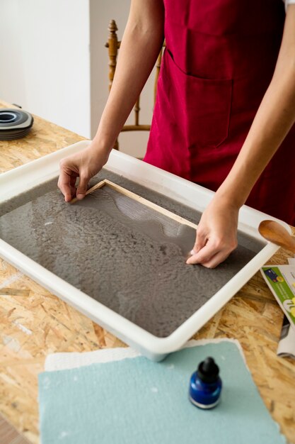 Main de femme dissolvant la moisissure dans la pâte à papier pour faire du papier