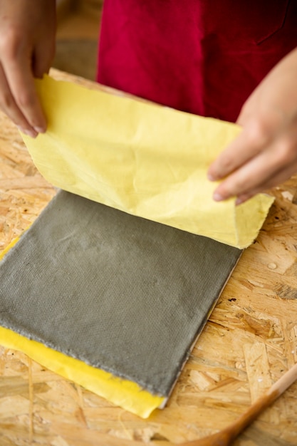 Photo gratuite main de femme enlevant le tissu jaune de la pâte à papier