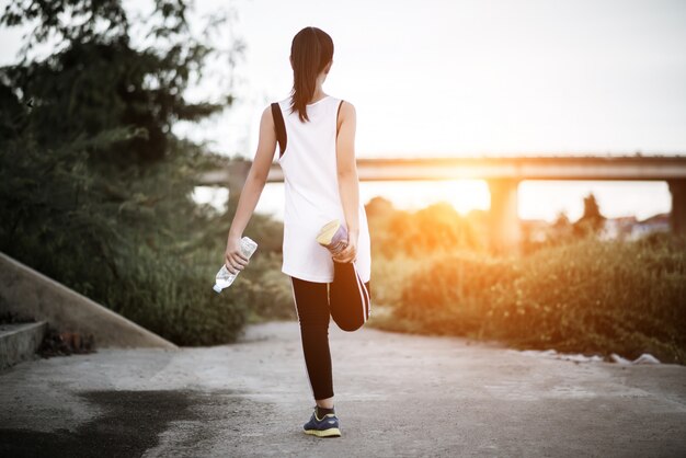 Main de femme jeune de remise en forme tenant la bouteille d&#39;eau après l&#39;exercice en cours d&#39;exécution