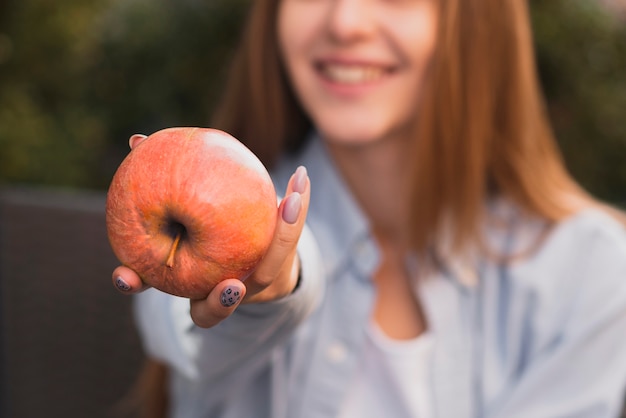 Main de femme offrant une pomme délicieuse
