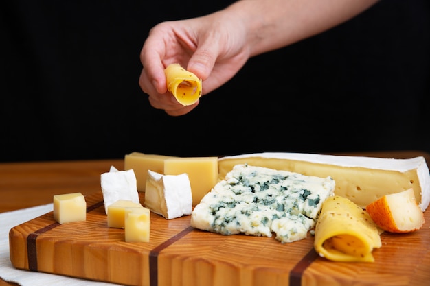 Photo gratuite main femme, prendre, tranche fromage, depuis, planche bois