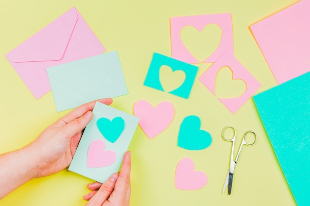 Photo gratuite main de femme préparant la carte de voeux forme coeur sur fond jaune