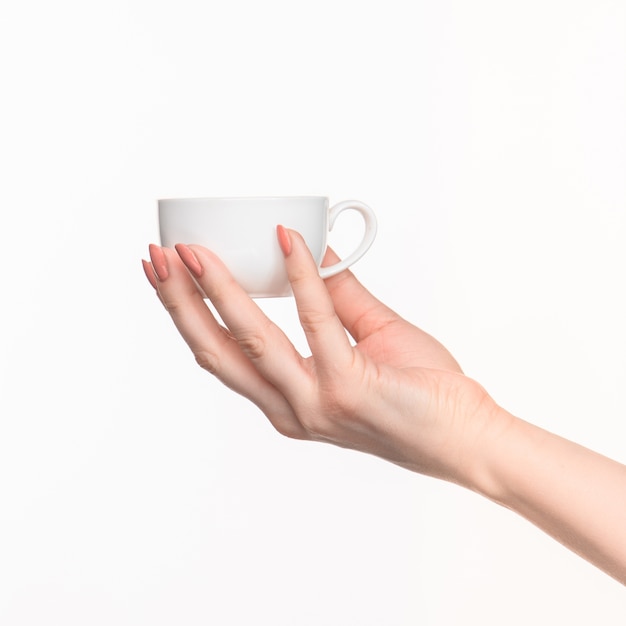 Main de femme avec une tasse blanche parfaite sur fond blanc