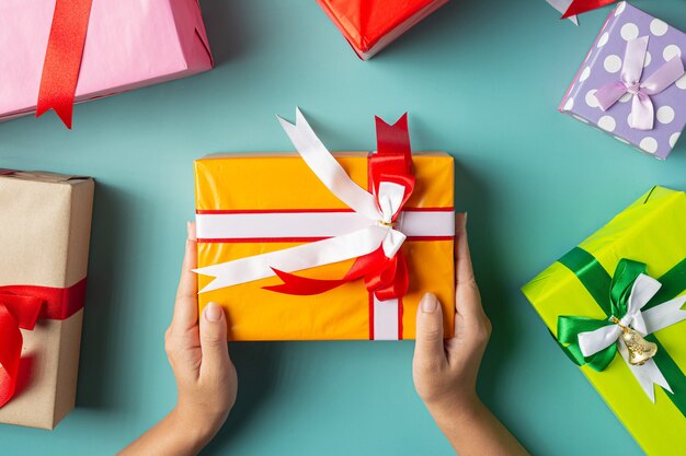 Main de femme tenant une boîte-cadeau sur un sol vert clair