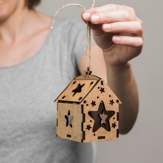 Main de femme tenant une petite maison brune