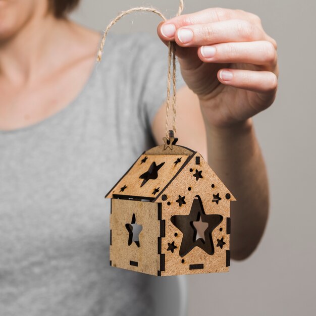 Main de femme tenant une petite maison brune